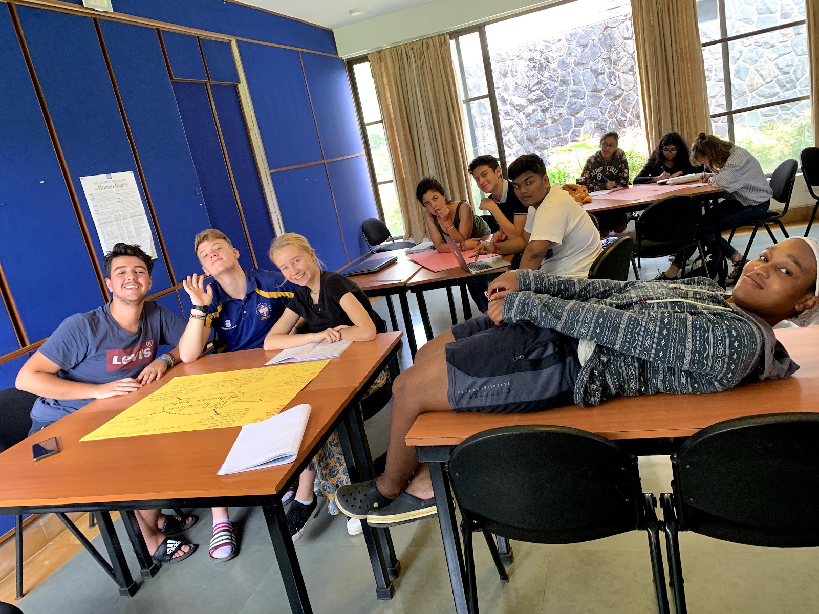 Students working around a table on a human-rights poster, with the Universal Declaration on the wall behind them